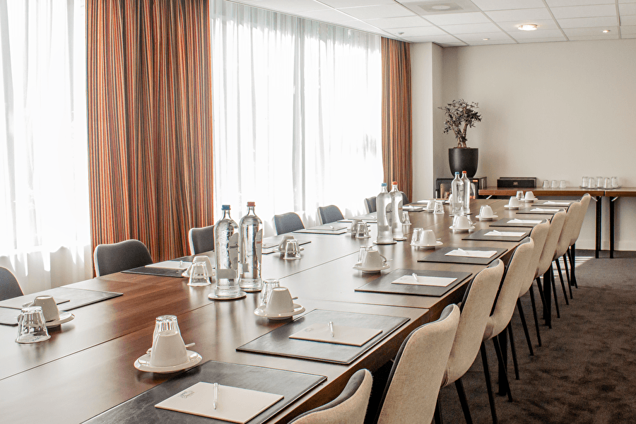 Stijlvolle vergaderzaal in Amrâth Grand Hotel Frans Hals, sfeervol ingericht met een lange tafel, comfortabele stoelen en luxe vergaderset-up.