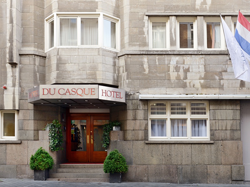 Voorzijde van Amrâth Hotel DuCasque in Maastricht, een klassiek gebouw met stenen gevel en vlaggen.