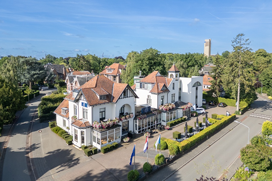 Amrâth Hotel Media Park in Hilversum, light facade with colorful flowers and outdoor seating.