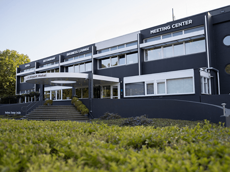 Amrâth Airport Hotel Rotterdam, modern gebouw met zakelijke uitstraling, brede trap en ruime entree.
