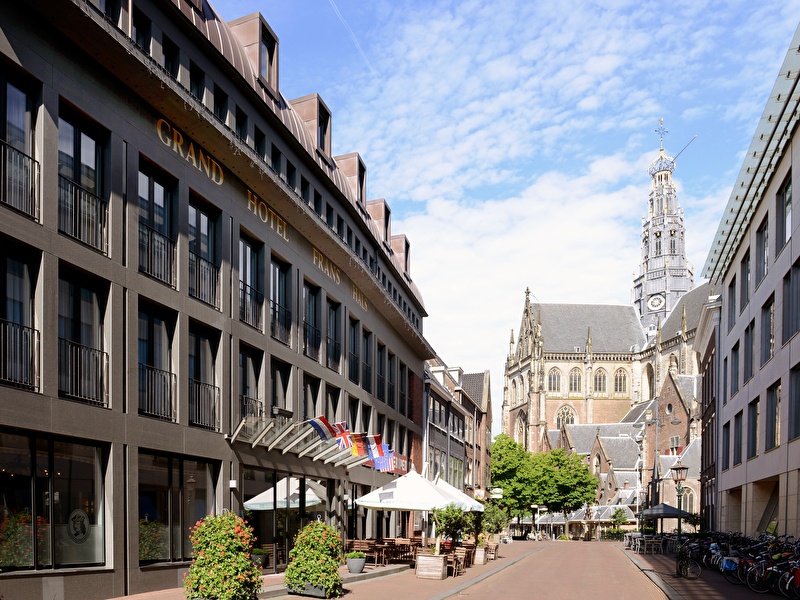 Amrâth Grand Hotel Frans Hals in Haarlem met op de achtergrond de Grote Kerk, moderne gevel met klassieke omgeving.