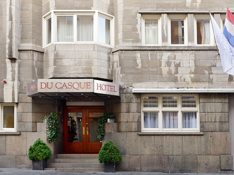 Voorzijde van Amrâth Hotel DuCasque in Maastricht, een klassiek gebouw met stenen gevel en vlaggen.