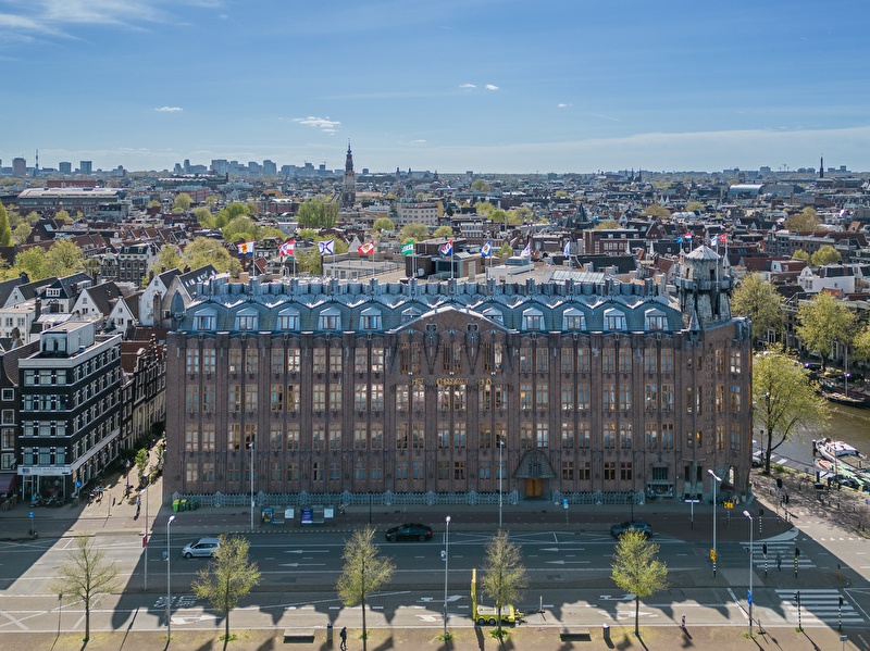 Grand Hotel Amrâth Amsterdam met stadspanorama op de achtergrond.