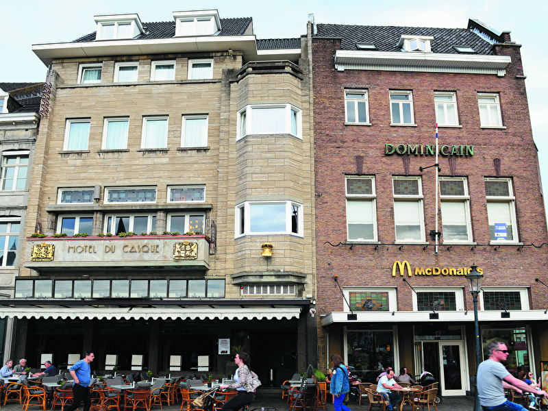 Front of Amrâth Hotel DuCasque in Maastricht, a classic building with a stone facade and flags.