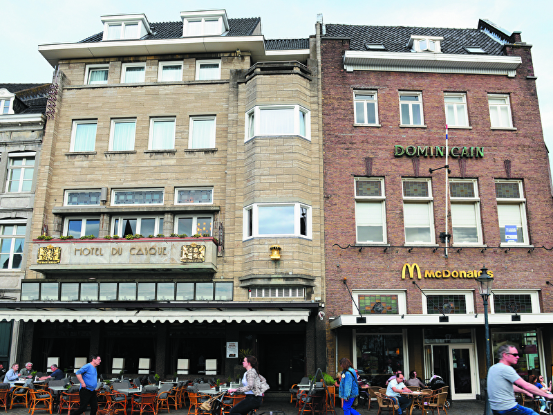 Front of Amrâth Hotel DuCasque in Maastricht, a classic building with a stone facade and flags.