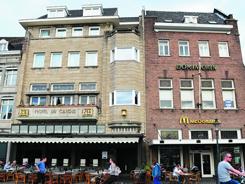 Voorzijde van Amrâth Hotel DuCasque in Maastricht, een klassiek gebouw met stenen gevel en vlaggen.