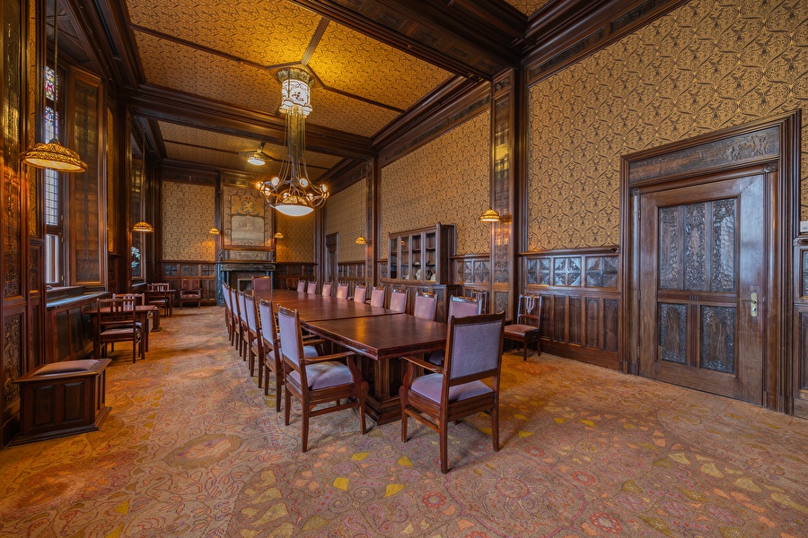 Een lange tafel is gedekt voor een formeel diner in de Beraadzaal van het Grand Hotel Amrâth Amsterdam.