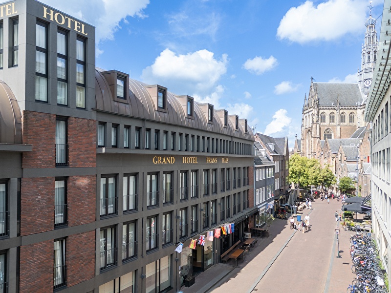Amrâth Grand Hotel Frans Hals in Haarlem met op de achtergrond de Grote Kerk, moderne gevel met klassieke omgeving.