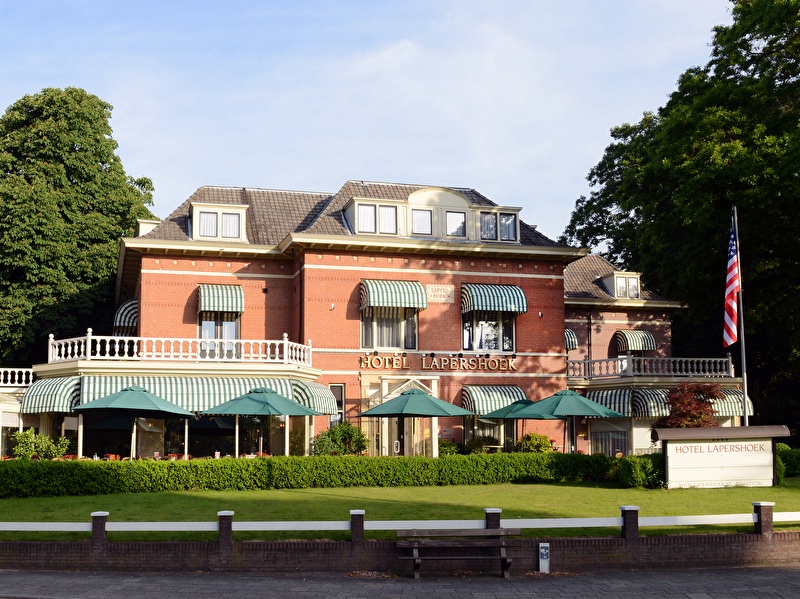 Exterieur aanzicht van Amrâth Hotel Lapershoek Arenapark in Hilversum, charmante villa met groene luifels.