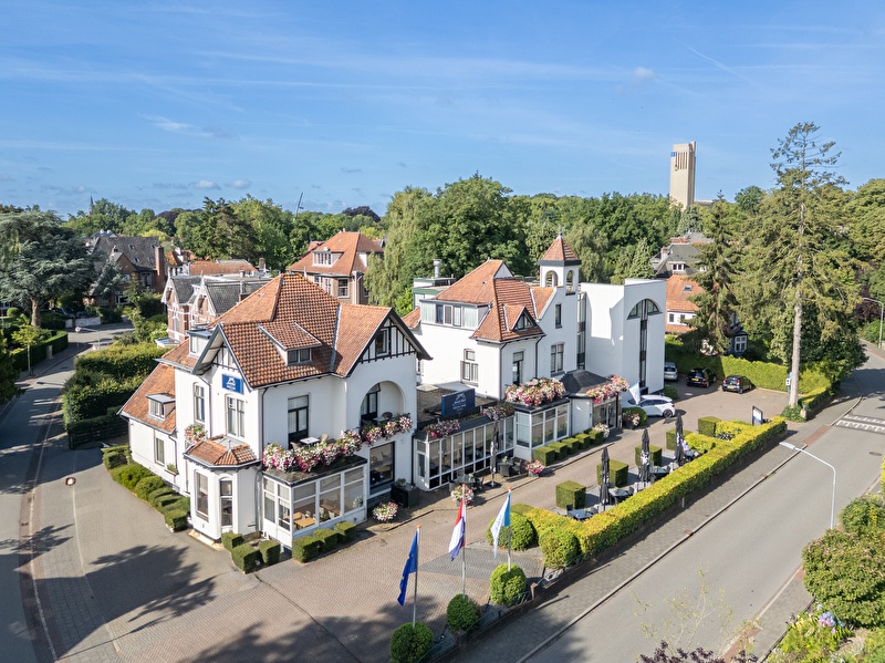 Amrâth Hotel Media Park in Hilversum, lichte gevel met kleurrijke bloemen en buitenzitplaatsen.