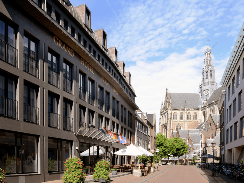 Amrâth Grand Hotel Frans Hals in Haarlem met op de achtergrond de Grote Kerk, moderne gevel met klassieke omgeving.