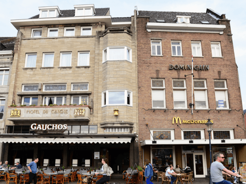 Voorzijde van Amrâth Hotel DuCasque in Maastricht, een klassiek gebouw met stenen gevel en vlaggen.