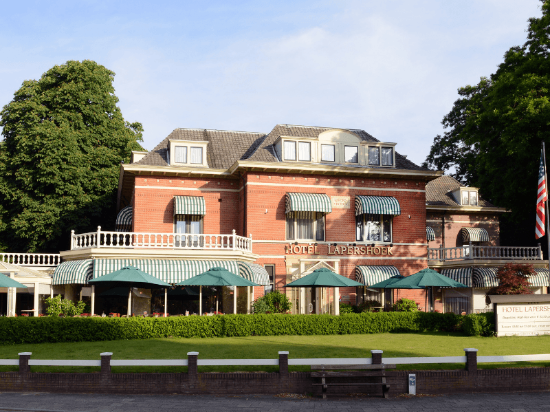 Exterieur aanzicht van Amrâth Hotel Lapershoek Arenapark in Hilversum, charmante villa met groene luifels.