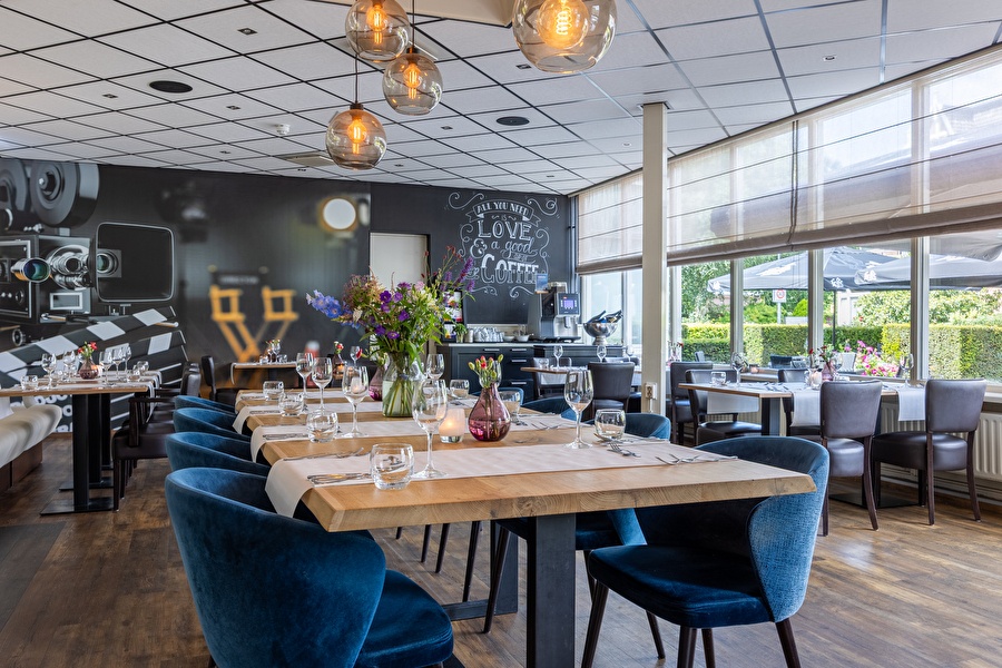 Sfeervol restaurant van Amrâth Hotel Media Park Hilversum met houten vloeren, gedekte tafels, grote ramen.