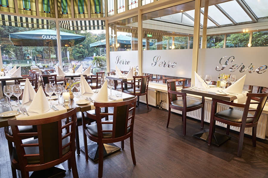Restaurant Vivaldi in Amrâth Hotel Lapershoek Hilversum met klassiek gedekte tafels, houten stoelen en uitzicht op het terras met parasols.