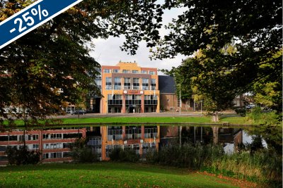 Amrâth Hotel Alkmaar overlooks a pond with trees in front of it, surrounded by greenery.
