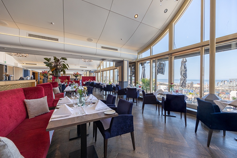 Restaurant Waves at the Kurhaus, met grote ramen en uitzicht op het water. Elegante tafels met witte linnen en bloemen.