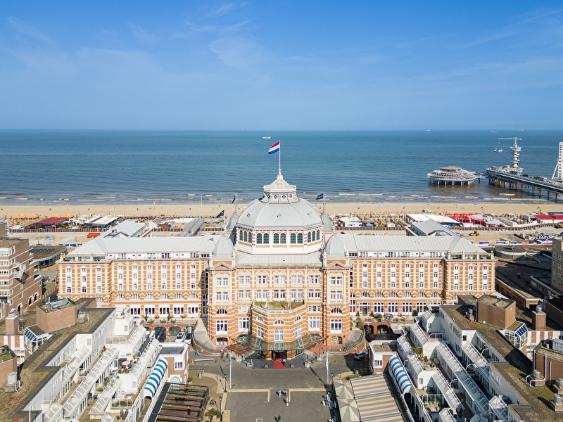 Luchtfoto van Grand Hotel Amrâth Kurhaus in Scheveningen met zicht op het strand, de Noordzee en de pier.