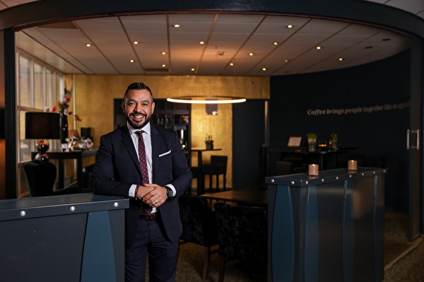Een man in een pak en stropdas staat voor een koffiezetapparaat in het Amrâth Berghotel Amersfoort.