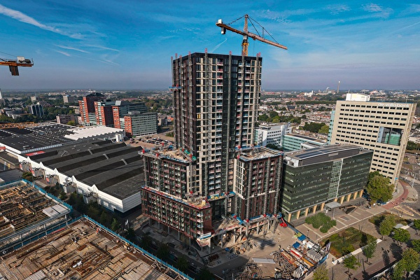 Een groot gebouw in aanbouw, de Amrâth Galaxy Jaarbeurshotel Utrecht, met een kraan op de achtergrond.